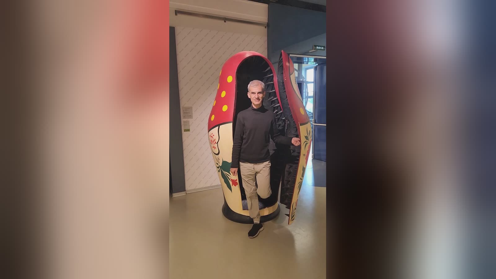 Un voyageur sort d'une matriochka géante rouge et blanche