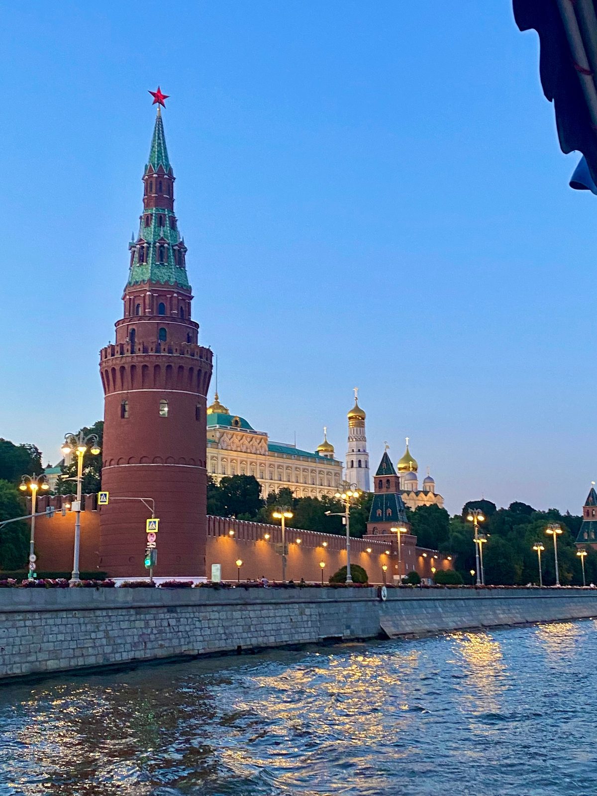 Une tour du Kremlin de Moscou et les coupoles dorées éclairées au crépuscule, vues depuis la Moskova